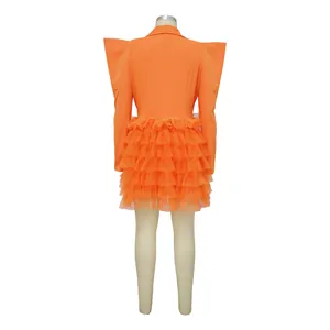 Back view of orange blazer dress with exaggerated shoulders and ruffled cake skirt