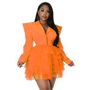 Detail view of the tiered orange tulle cake dress with sharp blazer style shoulders.