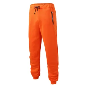 Detailed view of bright orange sports sweatpants featuring zipper pocket and drawstring waist