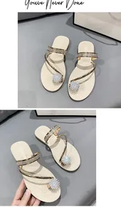 Detail view of elegant beige flat sandals featuring sparkling rhinestone flower and straps.