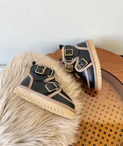 Close-up of children's fleece-lined winter snow boots with metal buckles on fur rug