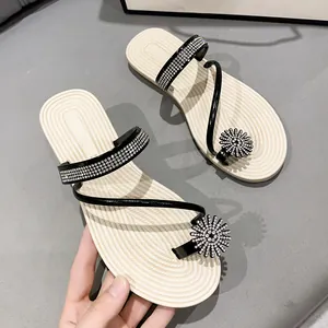 Close-up detail of stylish women's flat toe-loop sandals with rhinestone floral ornament