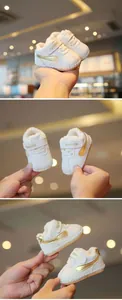 Close-up of white baby walker shoes with gold stripe and warm fleece lining details.