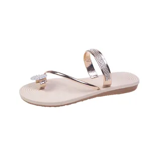 Detail showing sparkling rhinestone straps and metallic finish of champagne gold sandals.