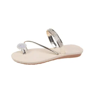 Elegant gold toe-loop sandals with sparkling rhinestone flower detail on beige flat sole