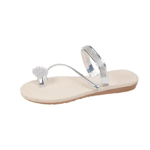Detailed macro shot of elegant silver rhinestone straps and flower charm on women's flat sandals