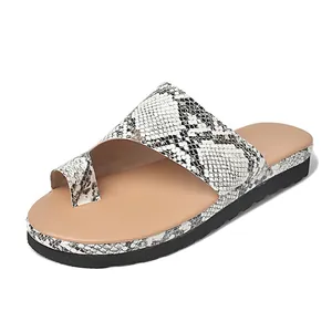 Nahaufnahme von Damen-Keilsandalen mit Zehenschlaufe und modischem Schlangenmuster
