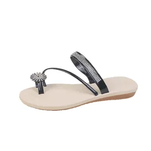 Close-up of elegant flat sandals with sparkling rhinestone straps and sunflower detail