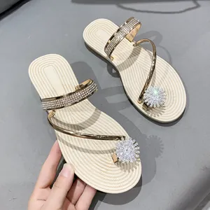 Elegant flat gold toe-loop sandals with sparkling rhinestones and flower ornament