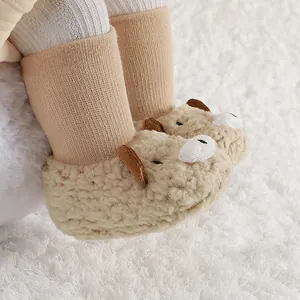 Primer plano de botas de bebé de forro polar beige con diseño de oso y textura suave