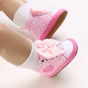 Detail von rosa Babyschuhen mit Leopardenmuster, großer Schleife und weicher Sohle