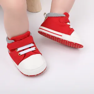 Nahaufnahme eines Babys in roten Canvas-Lauflernschuhen mit rutschfesten Gummisohlen für Halt