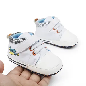 Weiße Baby-Lernlaufschuhe mit niedlicher Flugzeug-Stickerei in der Hand präsentiert