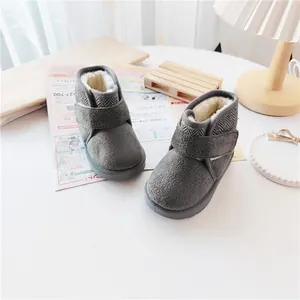 Close-up of cozy grey children's snow boots with warm faux fur lining on a white table