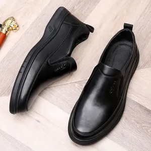 Detailopname van zwarte herenloafers van echt leer op een houten vloer met decoratie.