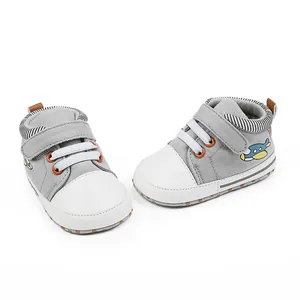 Detail der grauen Baby-Lauflernschuhe mit Flugzeug-Stickerei und weißer Kappe