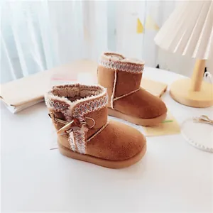 Detailed close-up of brown children's snow boots with faux fur lining and toggle