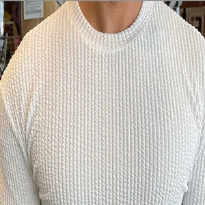 Close-up detail of white textured knit pattern on men's long sleeve sweater.