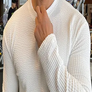 Close-up detail of men's white textured waffle knit sweater with long sleeves