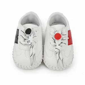 Vista superior de zapatos blancos para bebé con paneles laterales rojos y negros
