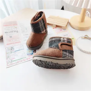 Close-up of brown children's snow boots with plaid accents and warm fleece lining
