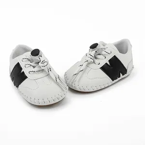 Vista macro de zapatos blancos para bebé con logo N negro y suela de goma antideslizante