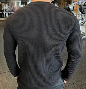 Close-up of black textured men's knit sweater showing the back and fine weave pattern.