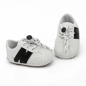 Vista detallada de zapatos para bebé blancos con logo N negro y cordones con tope