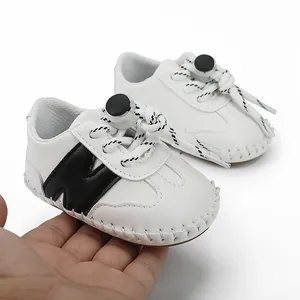 Detalle de los zapatos blancos para bebés con logo negro y suaves costuras a mano