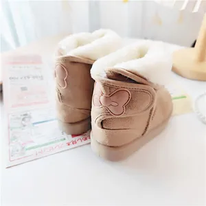 Close-up detail of children's winter boots with fluffy white fur and a pink bow on the heel