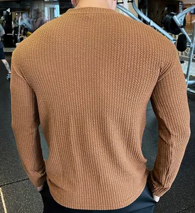 Detailed back view of men's brown textured knit long-sleeved sweater in a gym setting