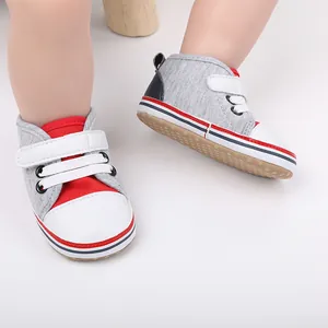 Vista detallada de zapatos de gateo para bebé en gris y rojo con suela blanda antideslizante.