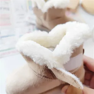 Detail of beige toddler snow boots with plush white faux fur lining and Velcro strap.