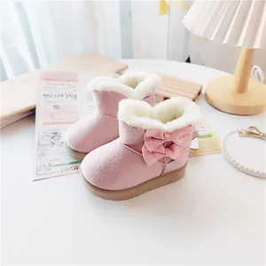 Detail view of pink children's snow boots with cute bows and warm white fur lining