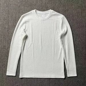 Close-up detail of the white textured waffle knit fabric and neckline of a men's sweater.