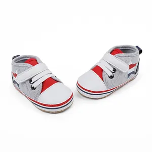 Par de zapatos grises de suela blanda para bebés con detalles rojos y patrones de estrellas