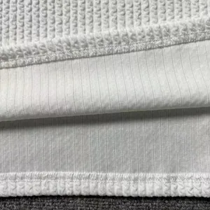 Close-up macro detail of white men's knit sweater fabric showing waffle and ribbed textures
