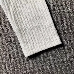 Macro detail showing the intricate white waffle knit texture of a men's long sleeve sweater