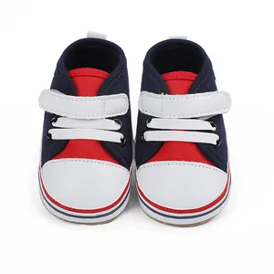 Detalle de zapatillas de bebé azul marino y rojo con suela blanda y cierres de velcro
