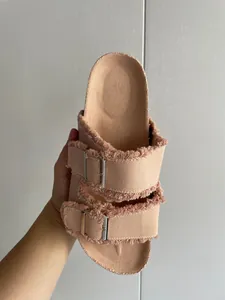 Detailed view of peach canvas slide sandal featuring fringed edges and double buckles