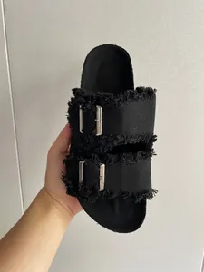 Detail view of black canvas slide sandal with frayed edges and double buckles