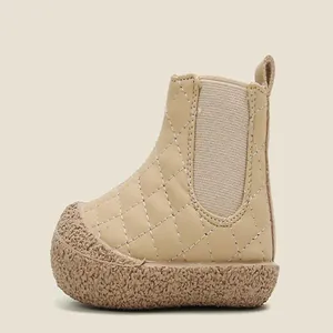 Side view of a quilted beige baby snow boot with a textured rubber sole