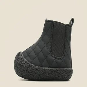 Side profile detail of a black quilted toddler snow boot with textured rubber sole