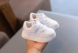 Macro view of white toddler sneakers featuring secure Velcro straps and durable soles.