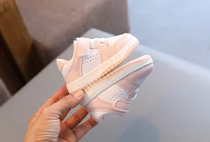 Close-up of stylish pink and white baby sneakers with soft anti-slip rubber soles for toddlers
