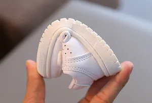 Close-up view of white soft-soled infant shoe demonstrating high bending flexibility