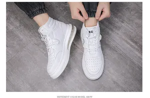Trendy men's white mid-top casual sneakers being laced up on a textured grey floor