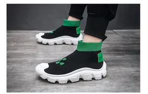 Side view detail of black breathable knit sock sneakers with green trim and chunky white sole