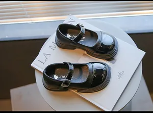 Vintage black girls' Mary Jane shoes with patent leather toe cap displayed on a book