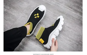 Detailed view of breathable black and yellow fly-knit sock shoes with thick white soles.